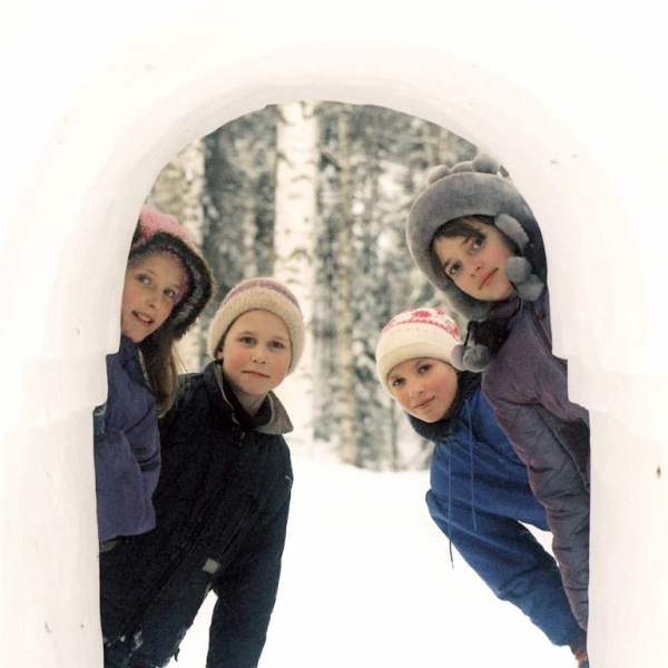 Kinder schauen durch einen Schneetunnel